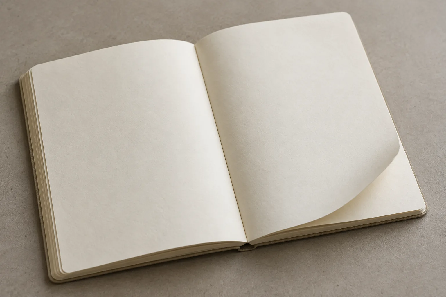 An open blank notebook on a table with all pages attached and continuous, while one page corner gently lifts.